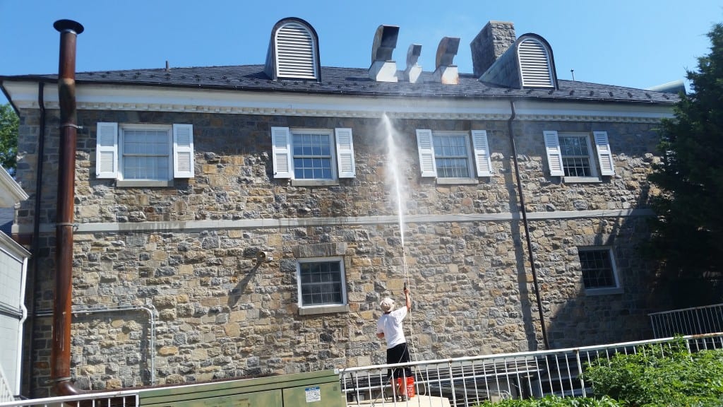 On a bright, sunny day with a clear blue sky, a person is diligently power-washing the side of a charming two-story brick building adorned with white shutters and several windows. Standing securely on a ledge below, they expertly direct a strong stream of water upwards to remove dirt and grime, revitalizing the building’s appearance.

Maryland Pro Wash brings this high level of expertise in pressure washing to residences and businesses across Harford County MD, Baltimore County MD, Cecil County MD, Howard County MD, Carroll County MD, Anne Arundel County MD. Additionally, we extend our professional services to Wilmington DE, New Castle County DE, and Delaware County PA. Whether it’s refreshing your home’s exterior or enhancing curb appeal for commercial properties like this beautiful multi-story building under the pristine sky—trust Maryland Pro Wash for superior results in all your pressure washing needs.