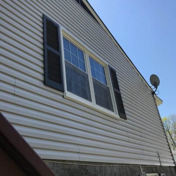 **View from Below: A Charming Home**

Looking up from the ground, you see a welcoming house with crisp white siding gleaming under the clear blue sky. The clean lines of the dark shutters dramatically frame a large, multi-pane window, giving the home an elegant yet inviting appearance. Mounted on the side of the house is a satellite dish, subtly blending into the immaculate exterior. 

This pristine look is maintained by Maryland Pro Wash, your go-to service for pressure washing across Harford County MD, Baltimore County MD, Cecil County MD, Howard County MD, Carroll County MD, Anne Arundel County MD as well as in Wilmington DE and New Castle County DE and stretching into Delaware County PA. Our expert team ensures that every inch of your home's exterior is spotless and radiant.

With Maryland Pro Wash’s meticulous attention to detail and commitment to quality service using environmentally-friendly techniques, your home can maintain its stunning presentation year-round.