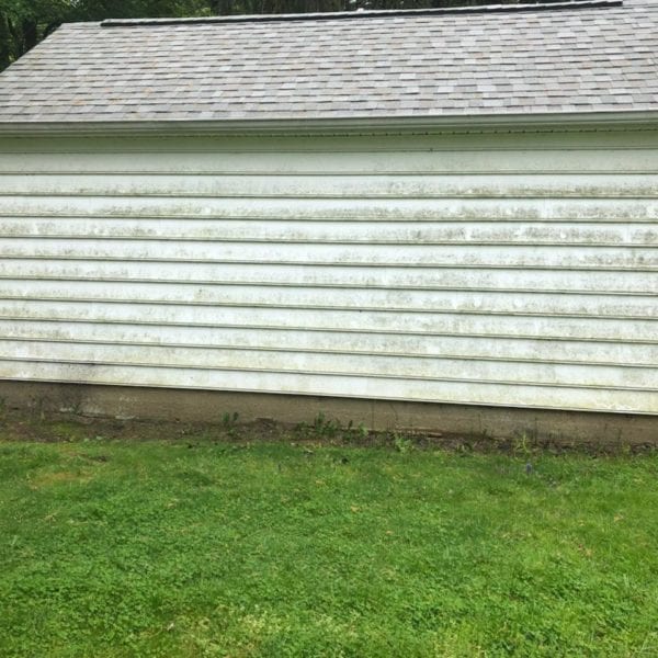 A weathered, white shed with horizontal siding and a shingled roof stands on a grassy lawn, its worn exterior telling tales of time and exposure to the elements. Positioned against a backdrop of lush trees, the shedding paint and discoloration are clear signs that it’s ready for a refresh. This picturesque yet aging scene is just what Maryland Pro Wash specializes in revitalizing. Serving Harford County MD, Baltimore County MD, Cecil County MD, Howard County MD, Carroll County MD, Anne Arundel County MD; as well as Wilmington DE, New Castle County DE; and Delaware County PA; Maryland Pro Wash offers professional pressure washing services to restore beauty and vibrancy to your property. Whether it's bringing life back to an old shed or enhancing the curb appeal of your home or business facade, their expert team is equipped to handle all your cleaning needs efficiently and effectively.
