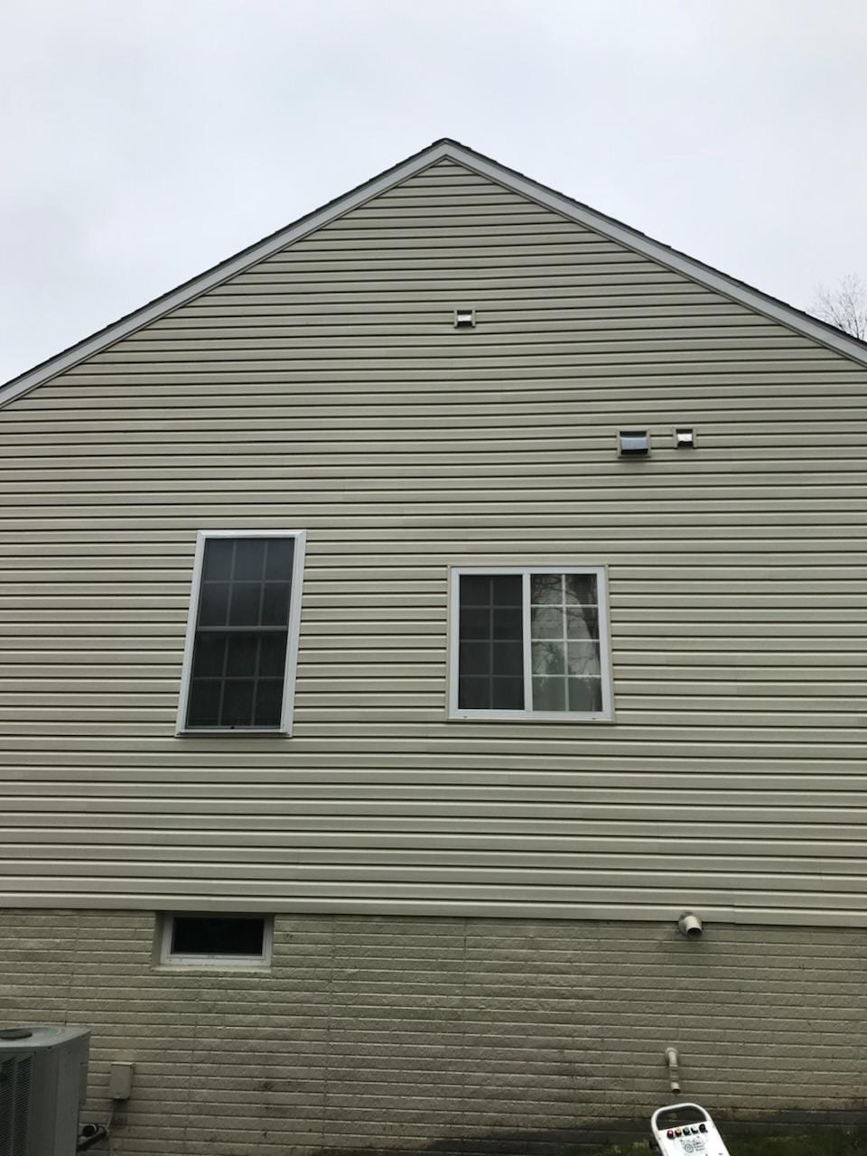 The image captures the exterior of a house featuring light gray siding with a pristine and uniform appearance, showcasing the transformative effects of professional pressure washing. 