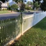 A white picket fence runs alongside a charming suburban street lined with trees and houses, where the sun casts gentle shadows on the grass. The leaves on the trees create a beautiful dappled effect on the sidewalk. For residents in need of maintaining such picturesque settings, Maryland Pro Wash provides top-notch pressure washing services to rejuvenate outdoor spaces across Harford County MD, Baltimore County MD, Cecil County MD, Howard County MD, Carroll County MD, Anne Arundel County MD. Additionally offering services in Wilmington DE, New Castle County DE, and Delaware County PA ensures that your property gleams with freshness no matter where you are located in these regions.