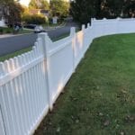 A white picket fence gently curves along a lush, grassy lawn, while a road with parked cars can be seen in the background. This picturesque scene is complemented by tall trees standing proudly in the distance beneath a clear sky. To ensure such beautiful vistas remain pristine, Maryland Pro Wash offers top-notch pressure washing services. Serving areas including Harford County, Baltimore County, Cecil County, Howard County, Carroll County, Anne Arundel County in Maryland; Wilmington in Delaware; New Castle County in Delaware; and Delaware County in Pennsylvania, they specialize in maintaining your outdoor spaces with their expert cleaning solutions.