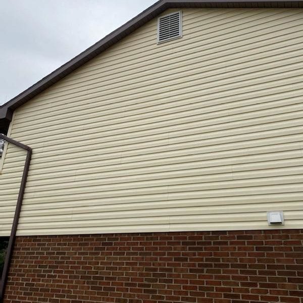Maryland Pro Wash specializes in transforming your property's appearance with expert pressure washing services. Imagine a building exterior featuring elegant beige vinyl siding on the upper half and sturdy red brick on the lower half, complemented by a small vent near the roof peak. Under an overcast sky, this setup can quickly get stained by elements such as dirt, algae, or mildew. Maryland Pro Wash is here to help residents and businesses in Harford County MD, Baltimore County MD, Cecil County MD, Howard County MD, Carroll County MD, Anne Arundel County MD—and extending our premium services to Wilmington DE, New Castle County DE, and Delaware County PA—revitalize their exteriors. Our expertise ensures your property shines brightly despite cloudy skies.