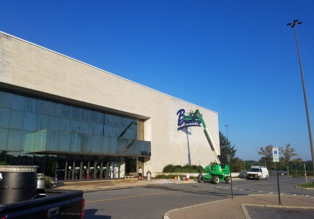 Employee Actively Pressure Washing Boscovs Mall And its Sign Using a Lift By Maryland Pro Wash